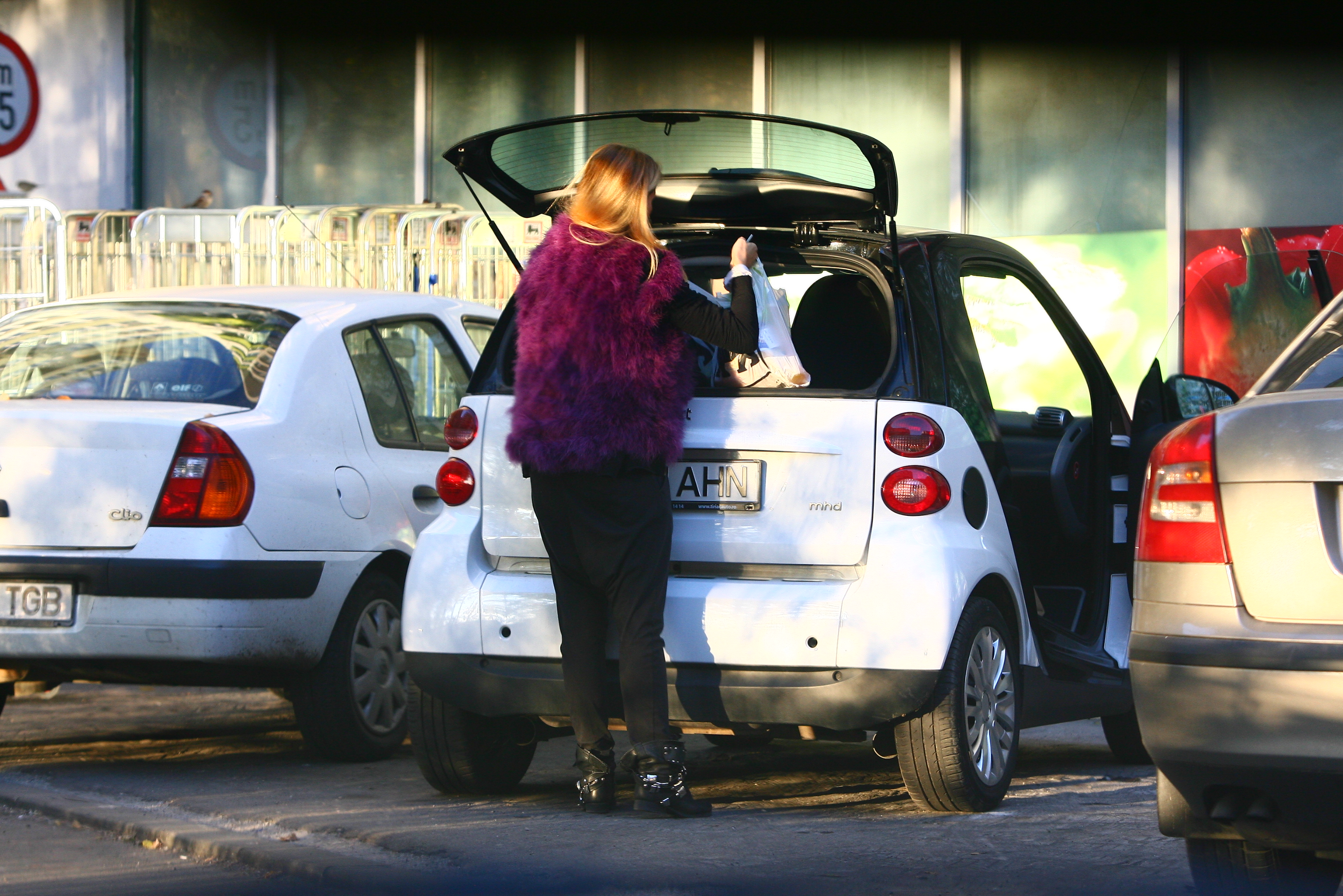 Andreea se grabeste sa aseze cumparaturile in portbagajul masinii