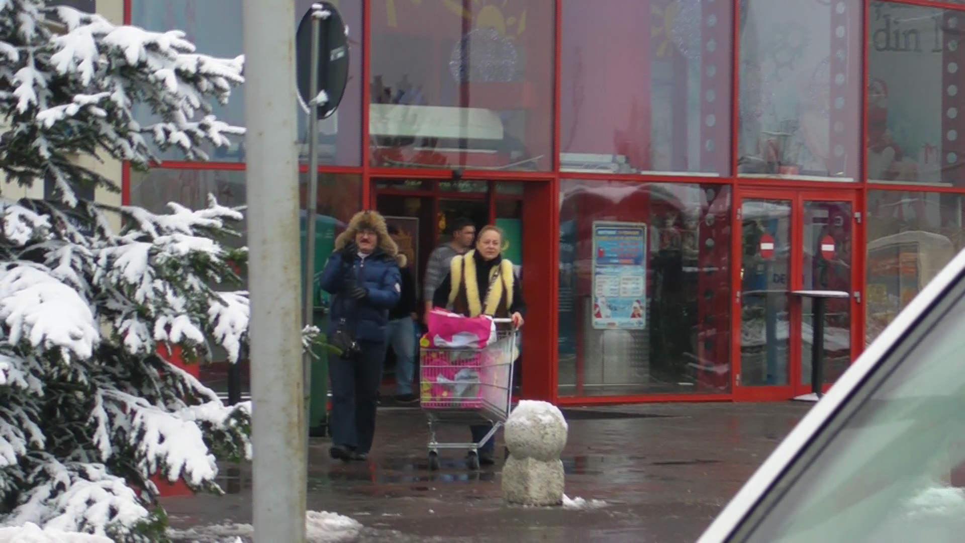 In timp ce sotia lui impinge cosul cu cumparaturi, Palade o urmeaza din spate