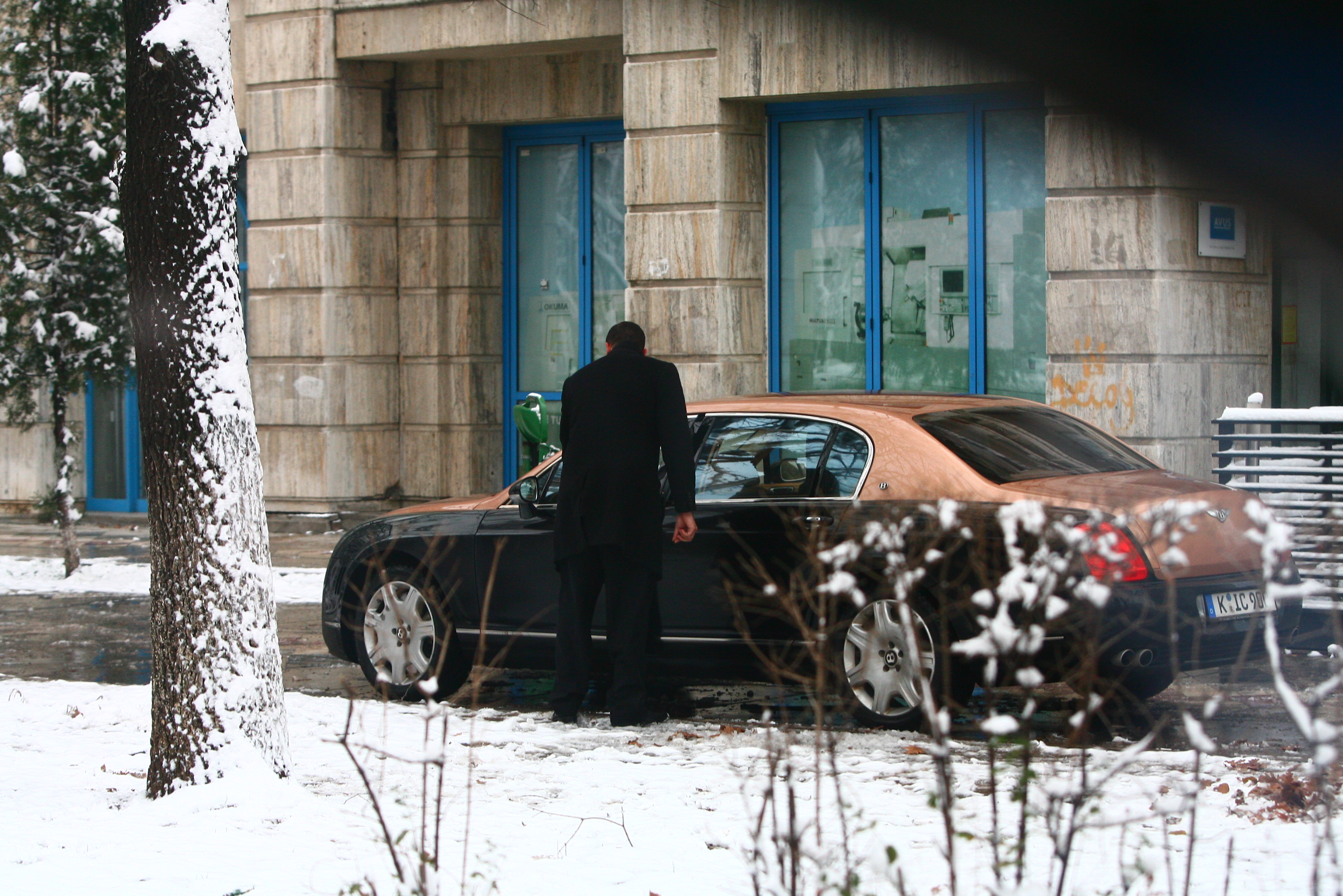 Soferul coboara din masina si merge sa-i deschida portiera sefului.