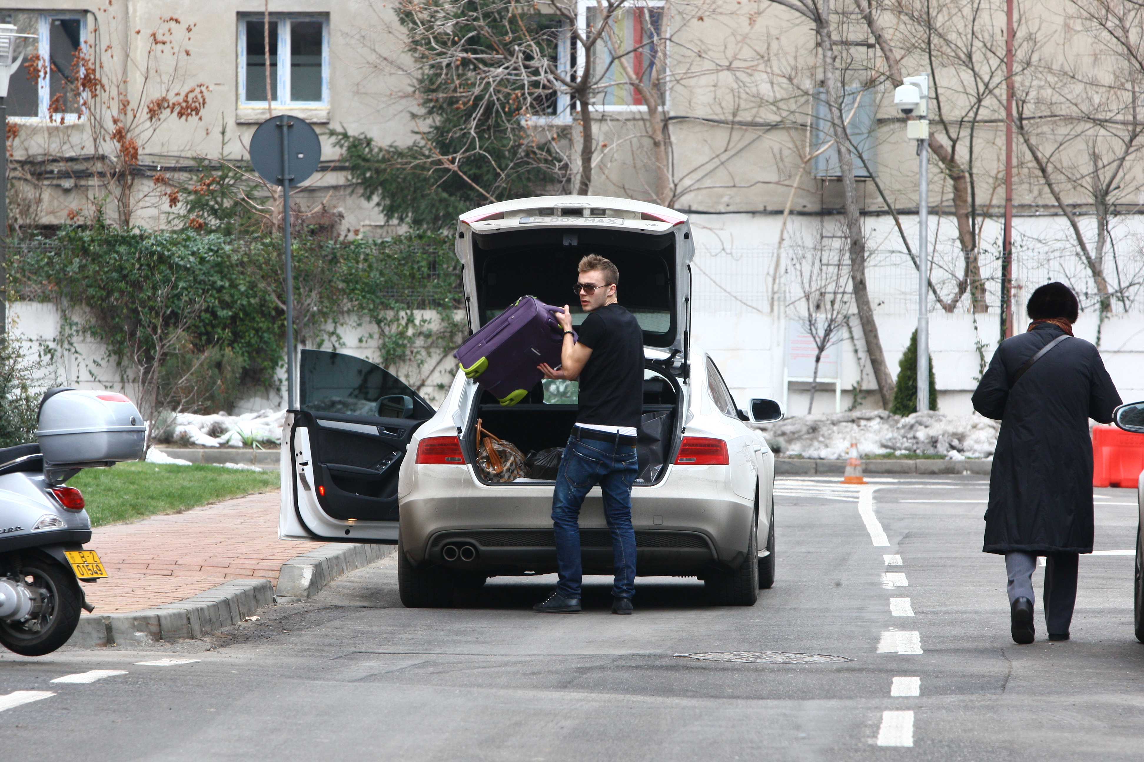 Fotbalistul se da jos din masina si scoate bagajul tinerei
