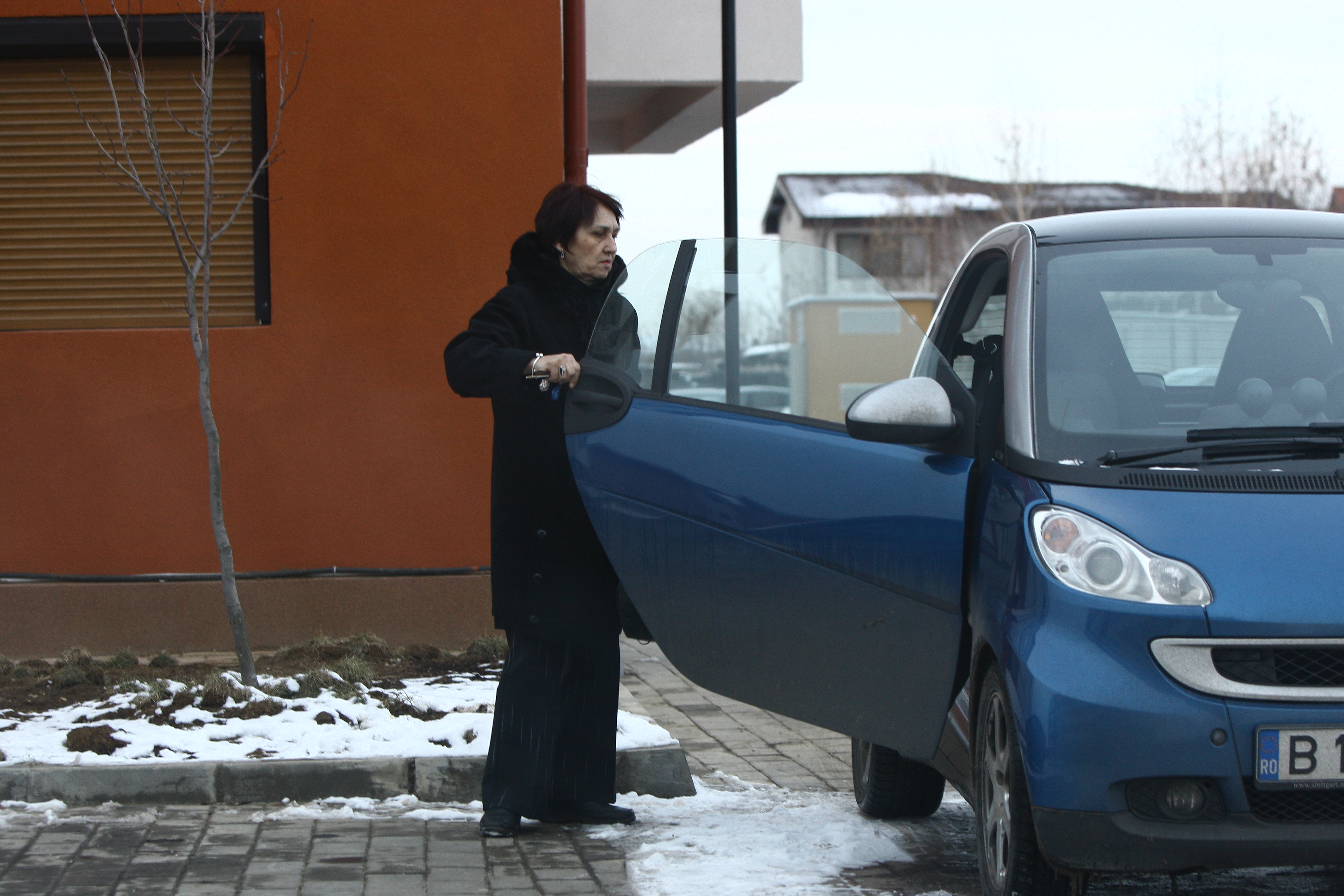 Femeia trecuta de prima tinerete, coboara din masina si se indreapta spre blocul unde locuieste Canu