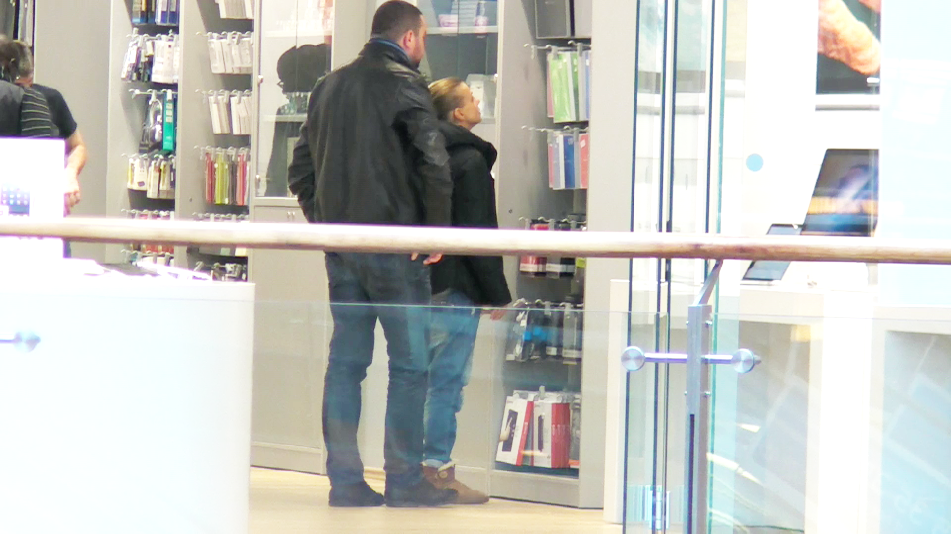 In timp ce vedeta TV se uita la diverse produse, tanarul o urmareste din spate, de teama sa nu o deranjeze