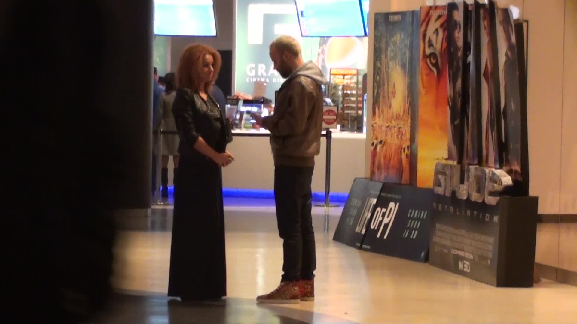 In timp ce artistul butoneaza telefonul mobil, partenera acestuia asteapta linistita