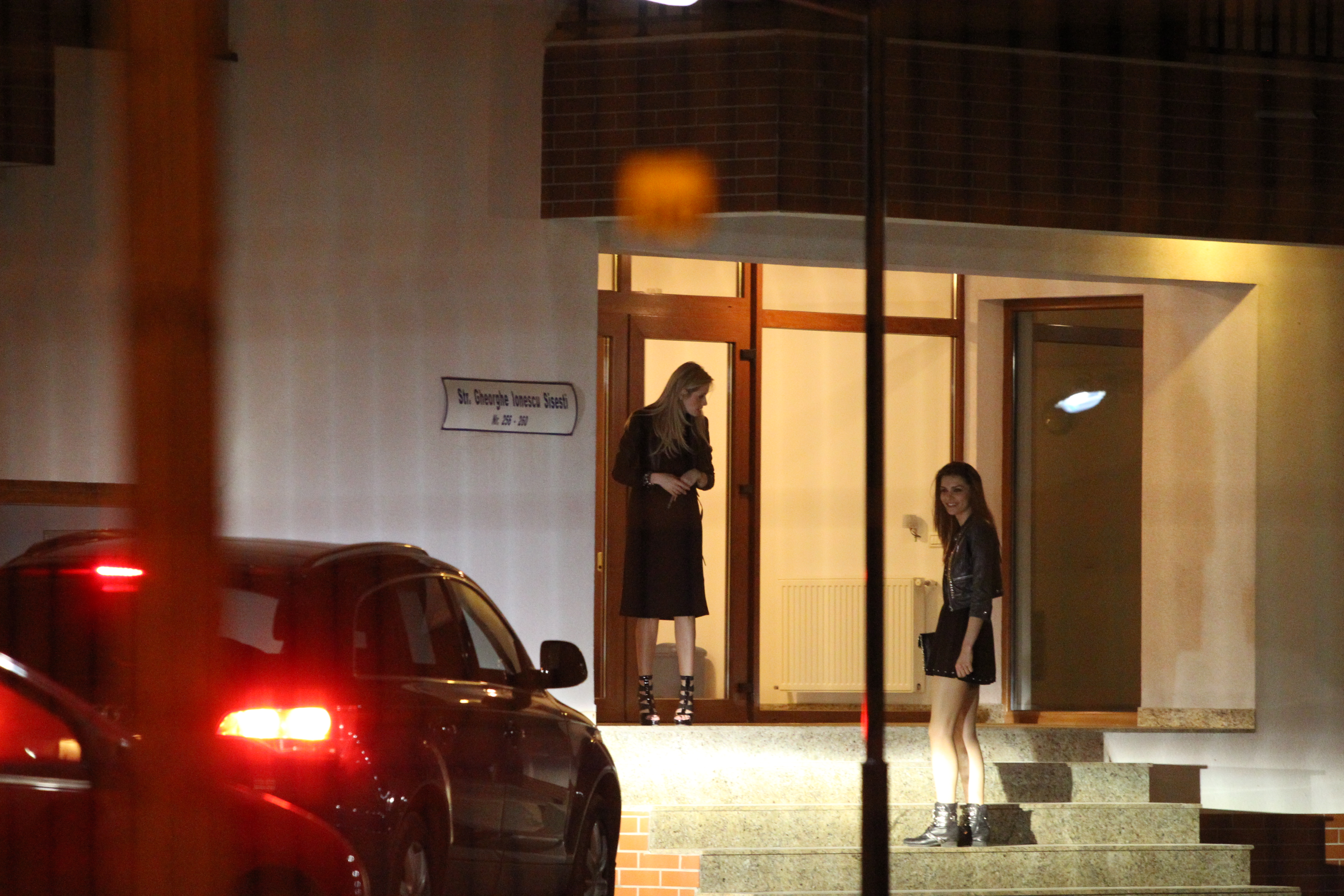 Blonda isi asteapta prietena, care se amuza si discuta cu unul dintre tineri