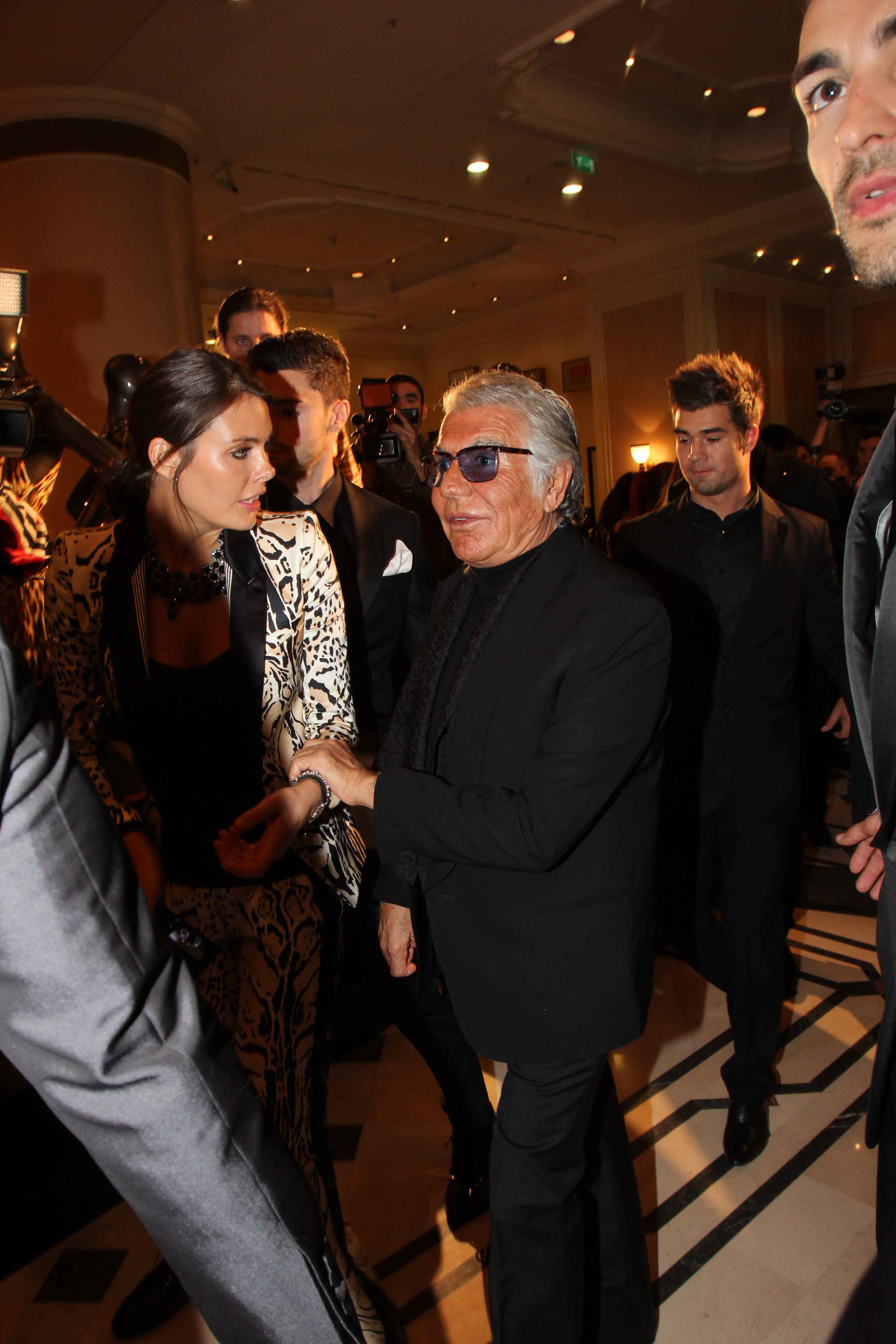 Roberto Cavalli se sprijina de una dintre fotomodelele care l-au insotit