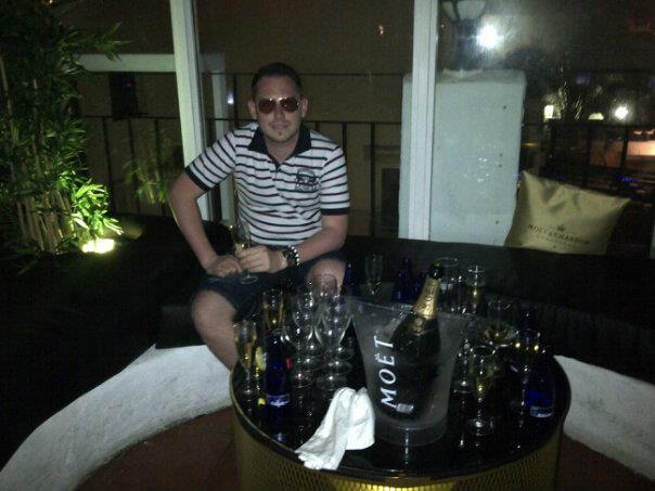 Versace se pozeaza la o masa plina cu sticle de sampanie