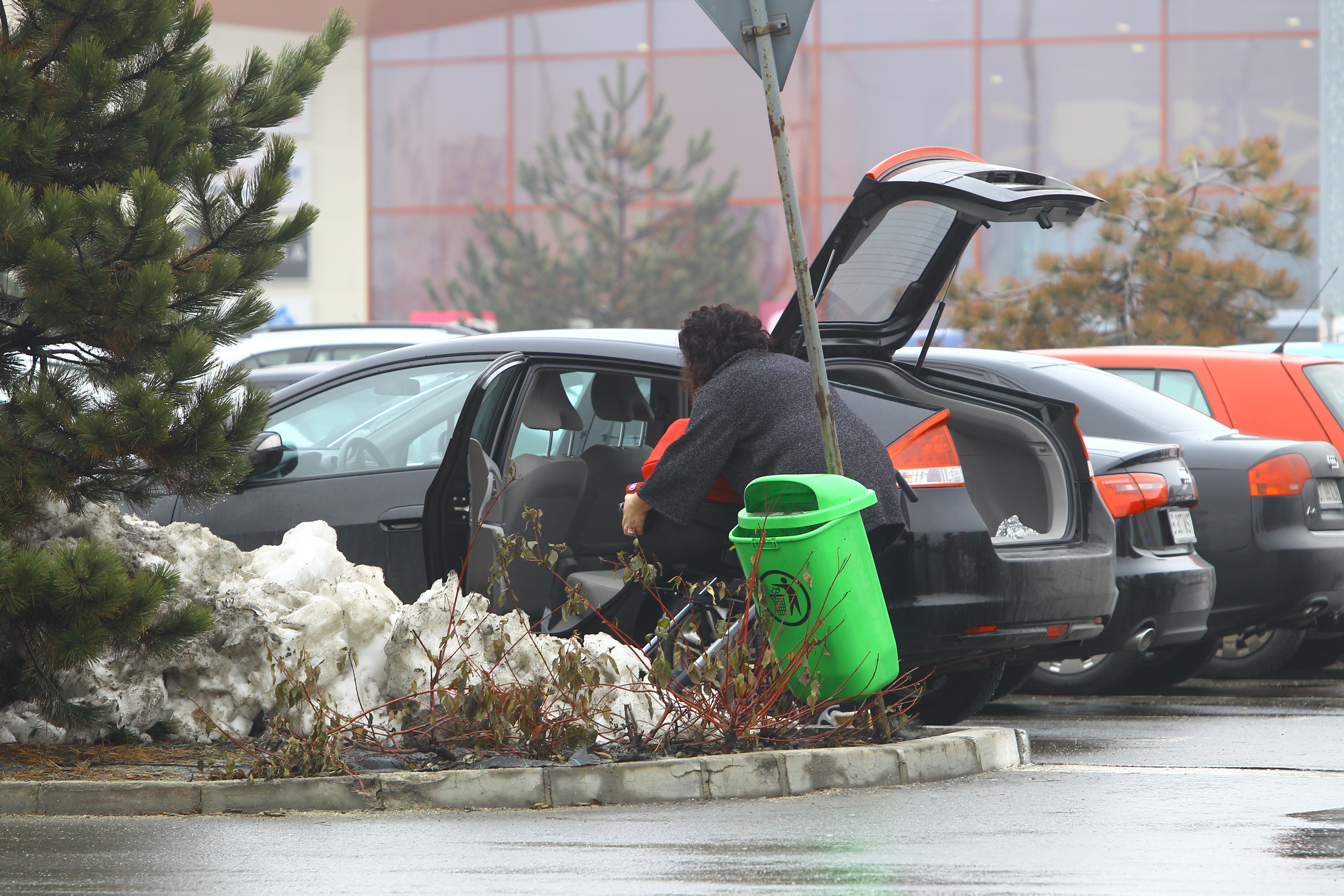 Femeia se chinuieste singura sa urce landoul in masina