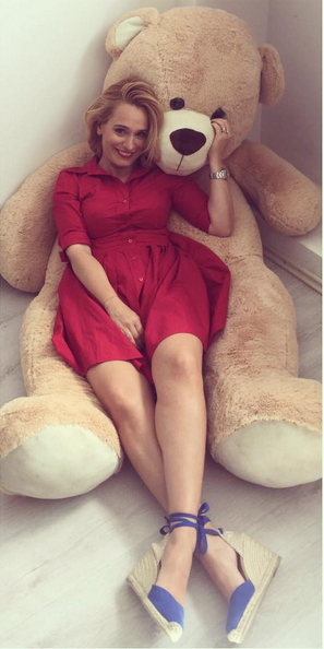 Andreea Esca stă întinsă pe un urs de pluş.