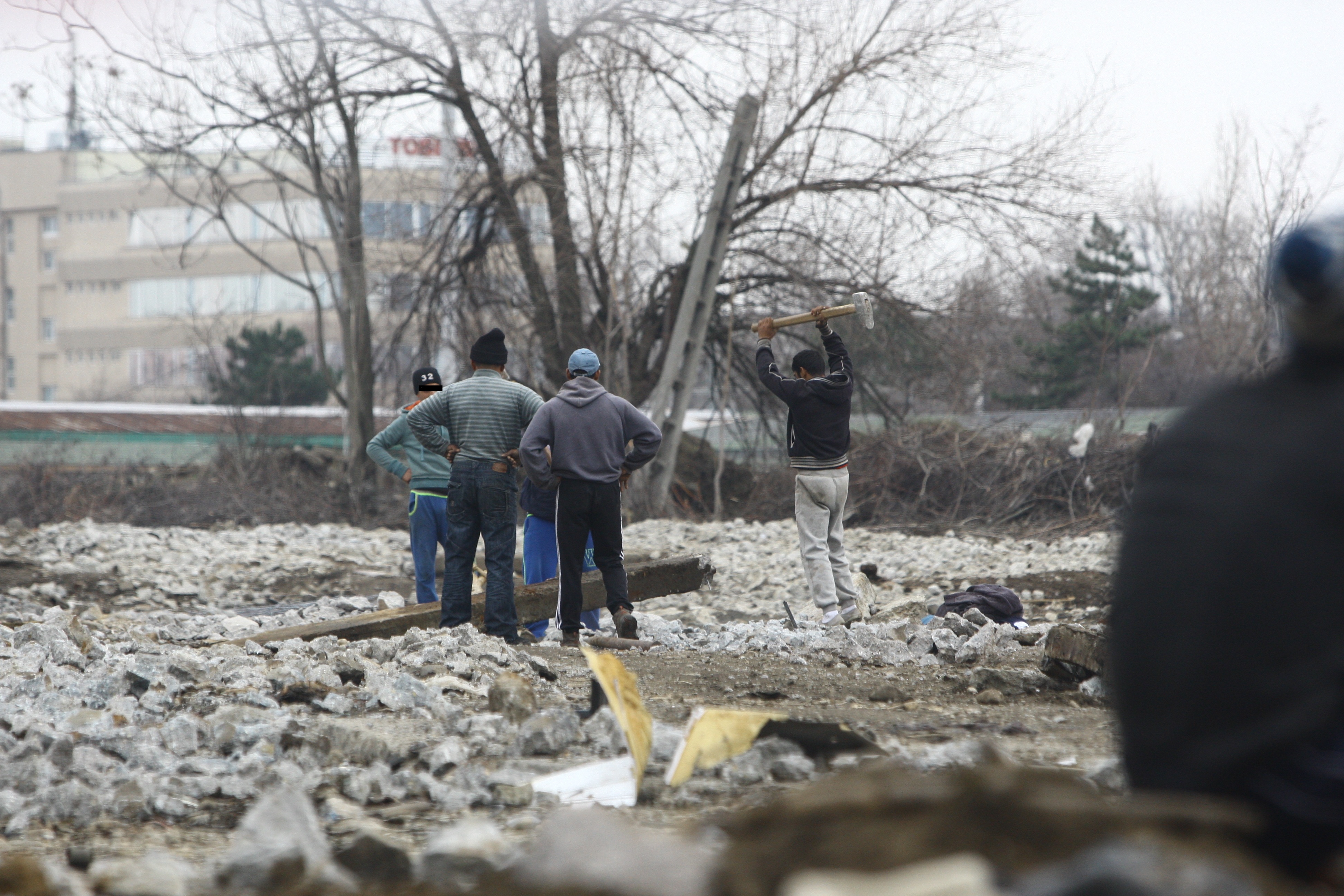 Truda. Mai multi s-au adunat langa un stalp pentru a lovi, cu randul, cu tarnacopul pentru a scoate fierul din betonul vechi