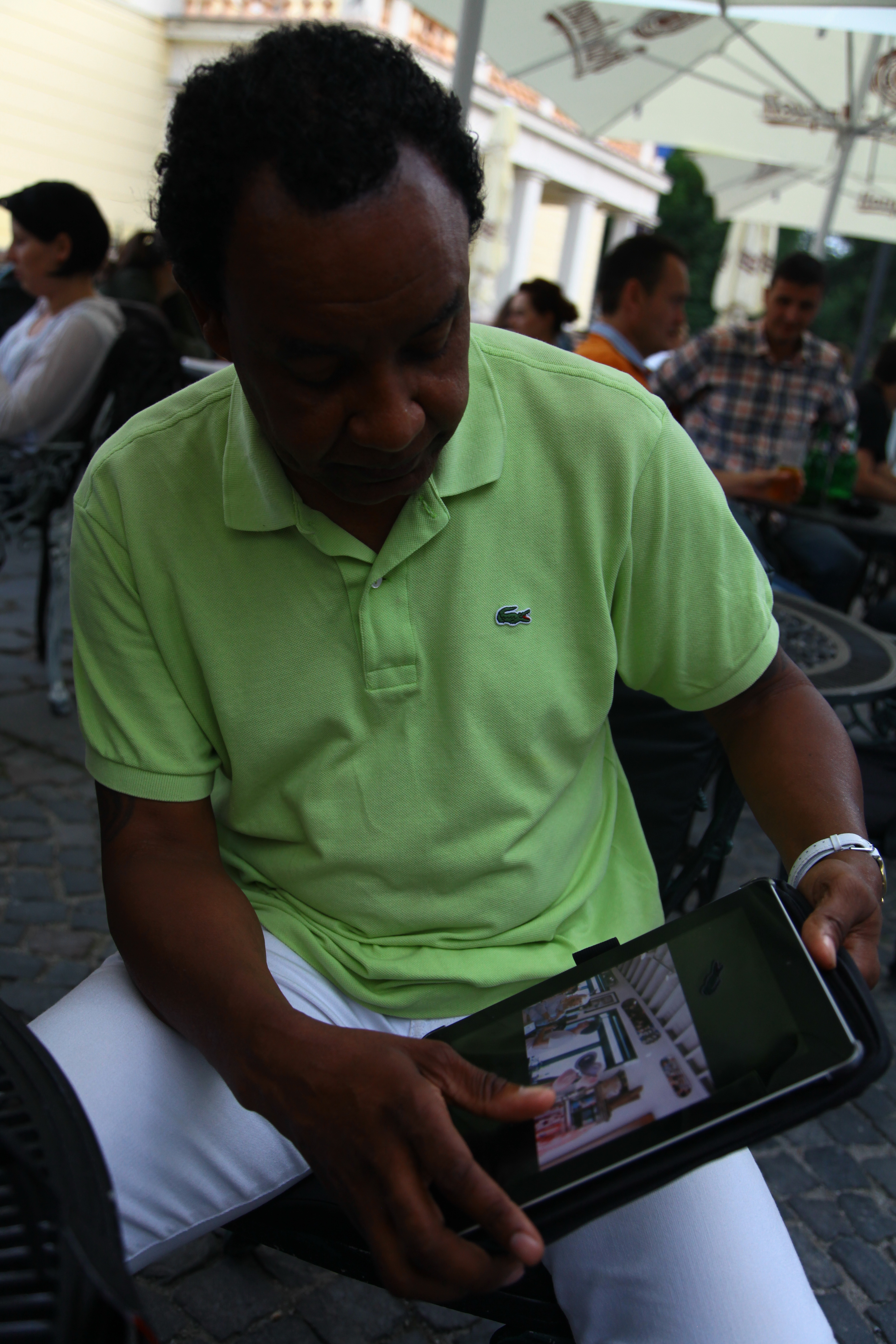 Roberto Rabanne, pe o terasa din Sibiu, aratand pozele stocate in tableta