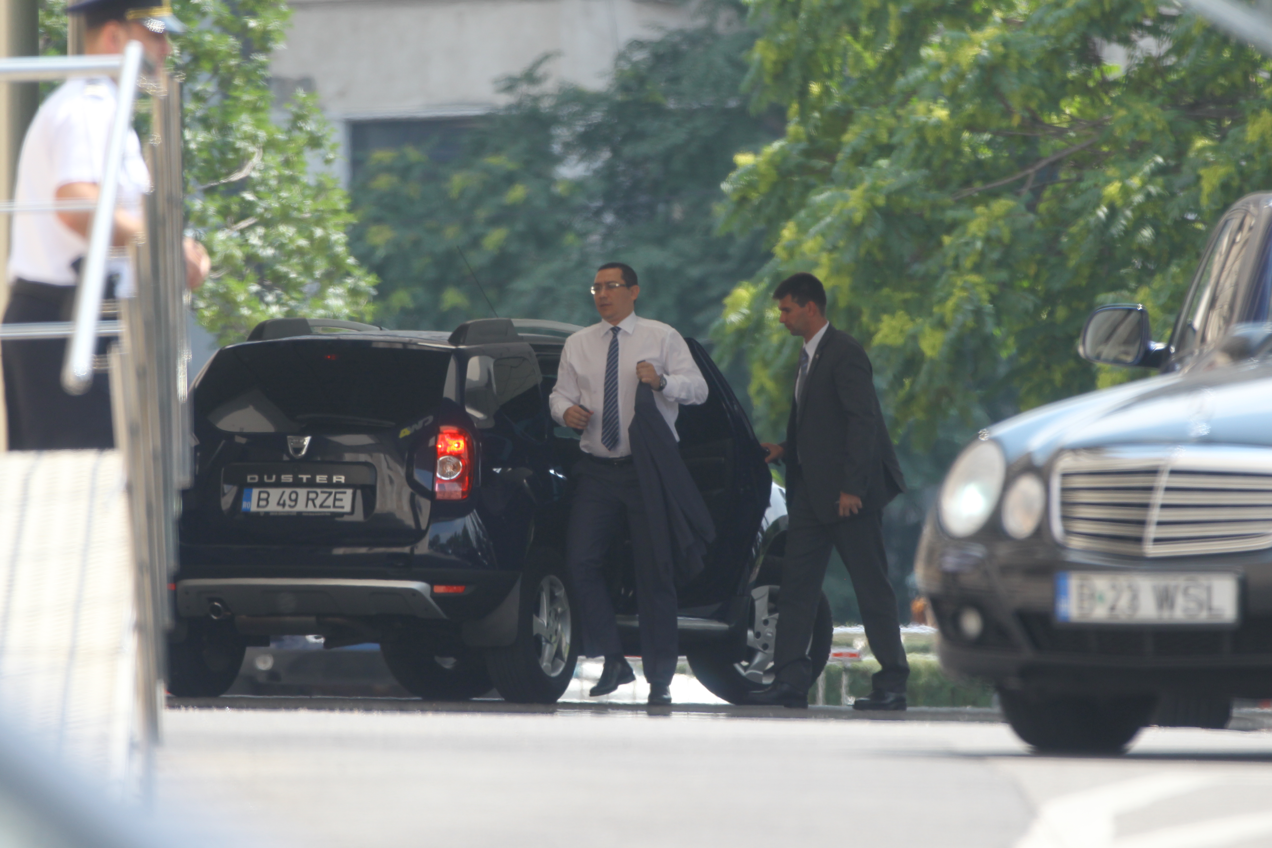 Premierul coboara grabit din masina si se indreapta spre cladirea Guvernului