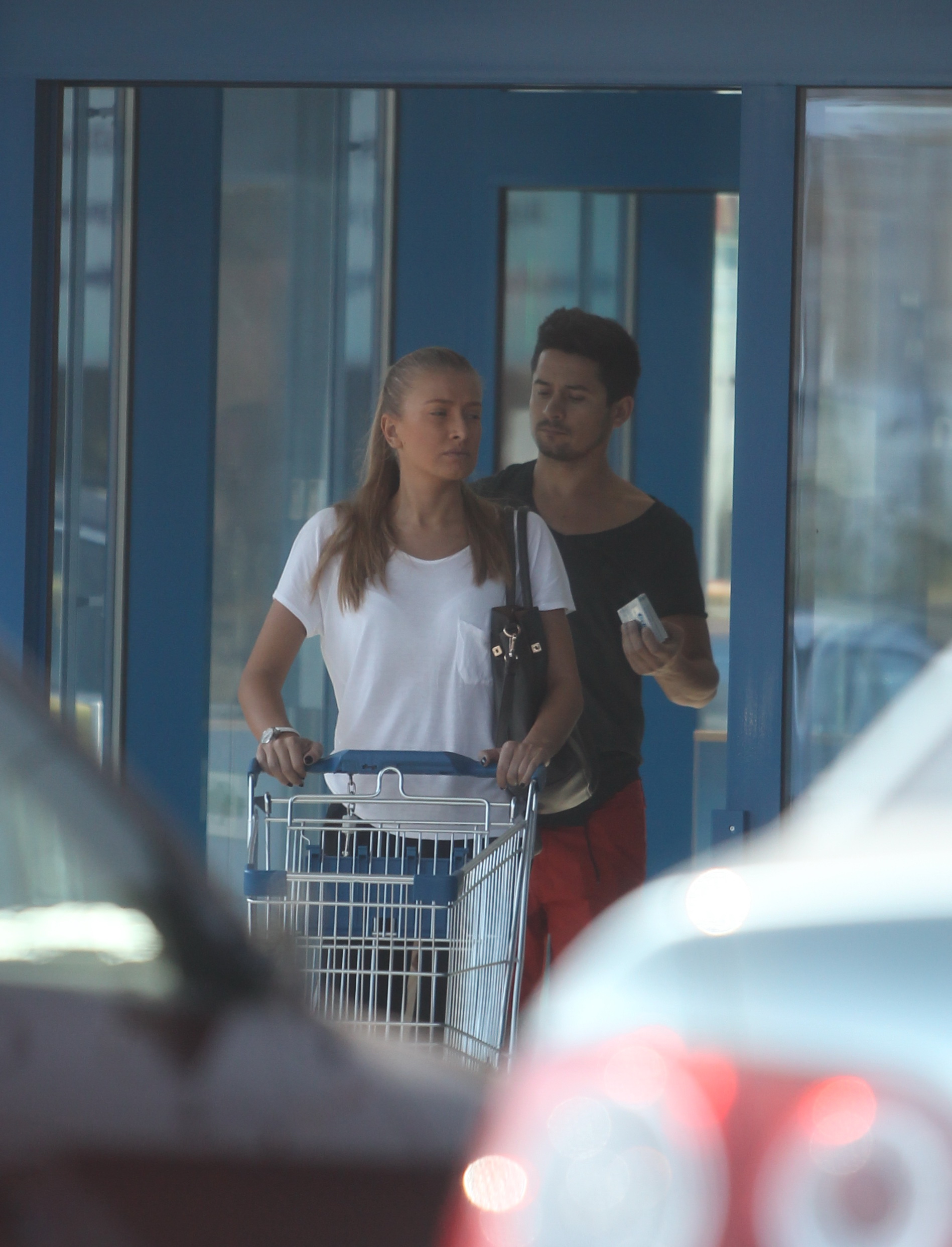 Prietena lui Tache Becali duce caruciorul la locul lui, in timp ce barbatul cara pungile cu cumparaturi