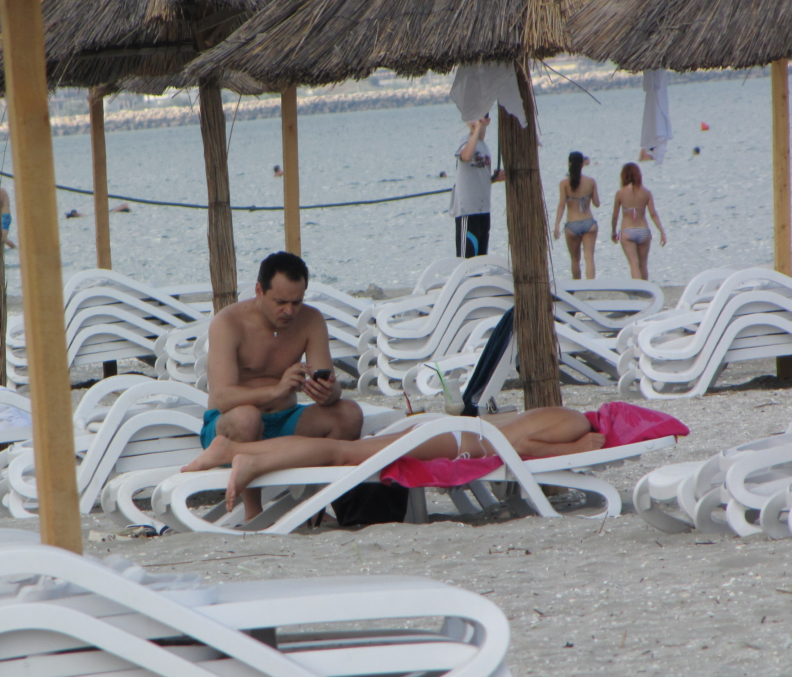 In timp ce partenera lui blonda se bronza pe sezlong, milionarul isi facea de treaba, langa ea, cu telefonul mobil