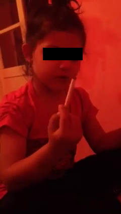 Fetita se uita la tigara sa vada cat mai are din ea