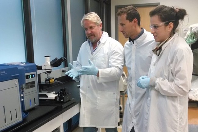 Andrew Conrad, seful Google X, le arata colegilor sai, Alberto Vitari si Marija Pavlovic niste instrumente pe care le vor folosi in cercetare