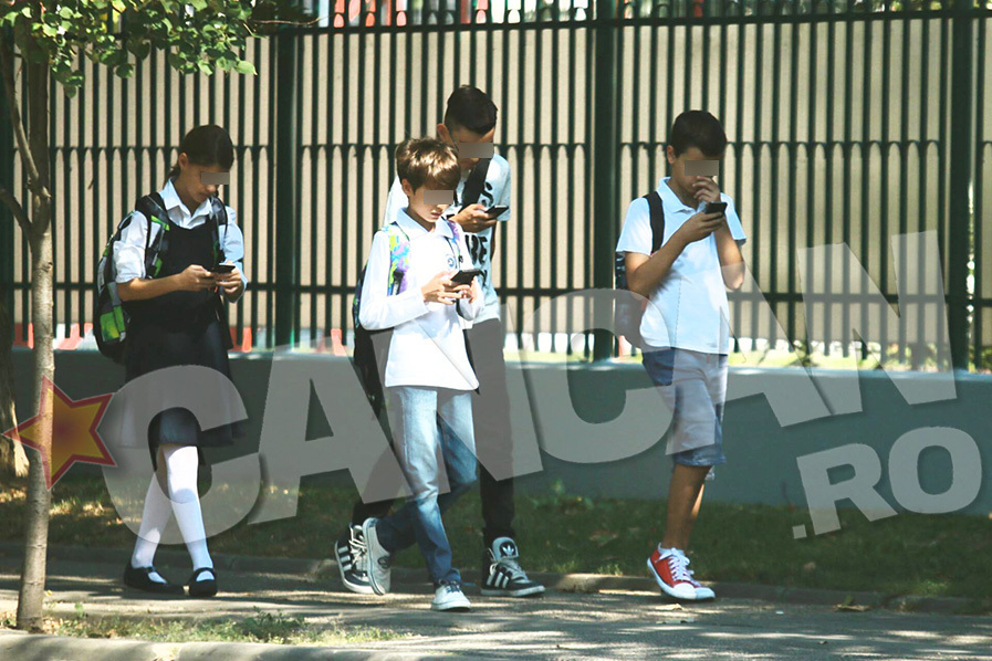 Toţi cei patru elevi sunt concentraţi la telefoanele lor mobile.