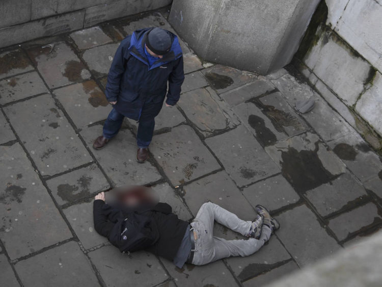 Un bărbat rănit stă întins pe jos.