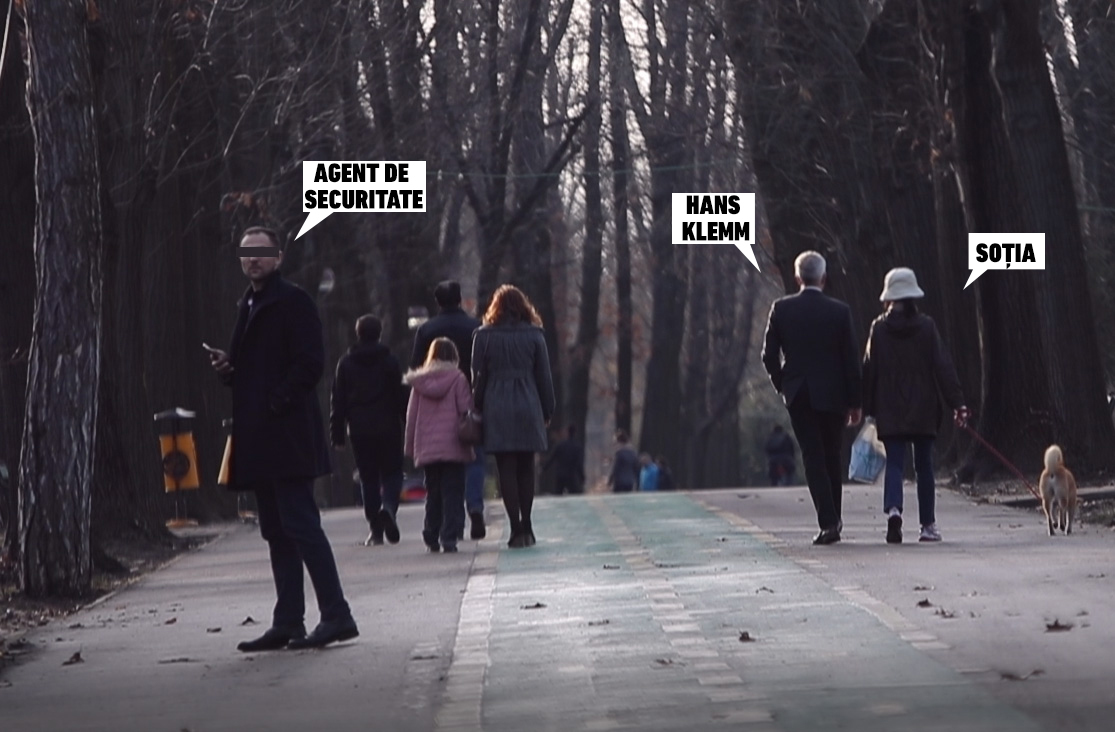 Un agent de securitate al ambasadorului SUA se uită speriat în spate, în timp ce Hans Klemm şi soţia lui îşi plimbă relaxaţi căţelul