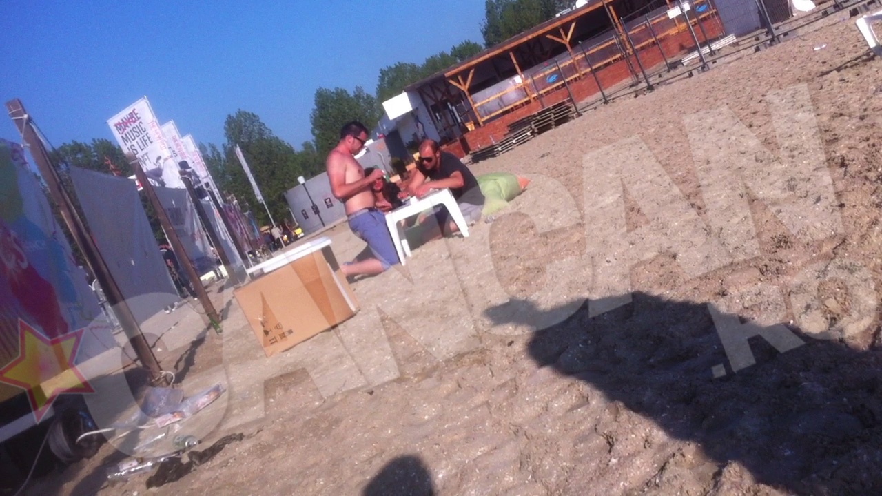 Unul dintre barbati presara pe masa improvizata un praf alb, pe care incepe sa-l aranjeze