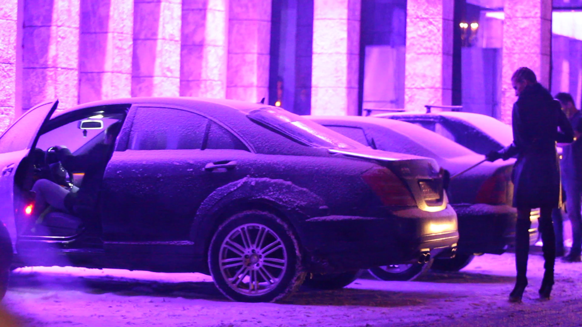 Barbatul se refugiaza in caldura masinii, in timp ce tanara continua sarguincioasa treaba. Acorda o deosebita atentie curatarii zapezii de pe numar si de pe stopuri