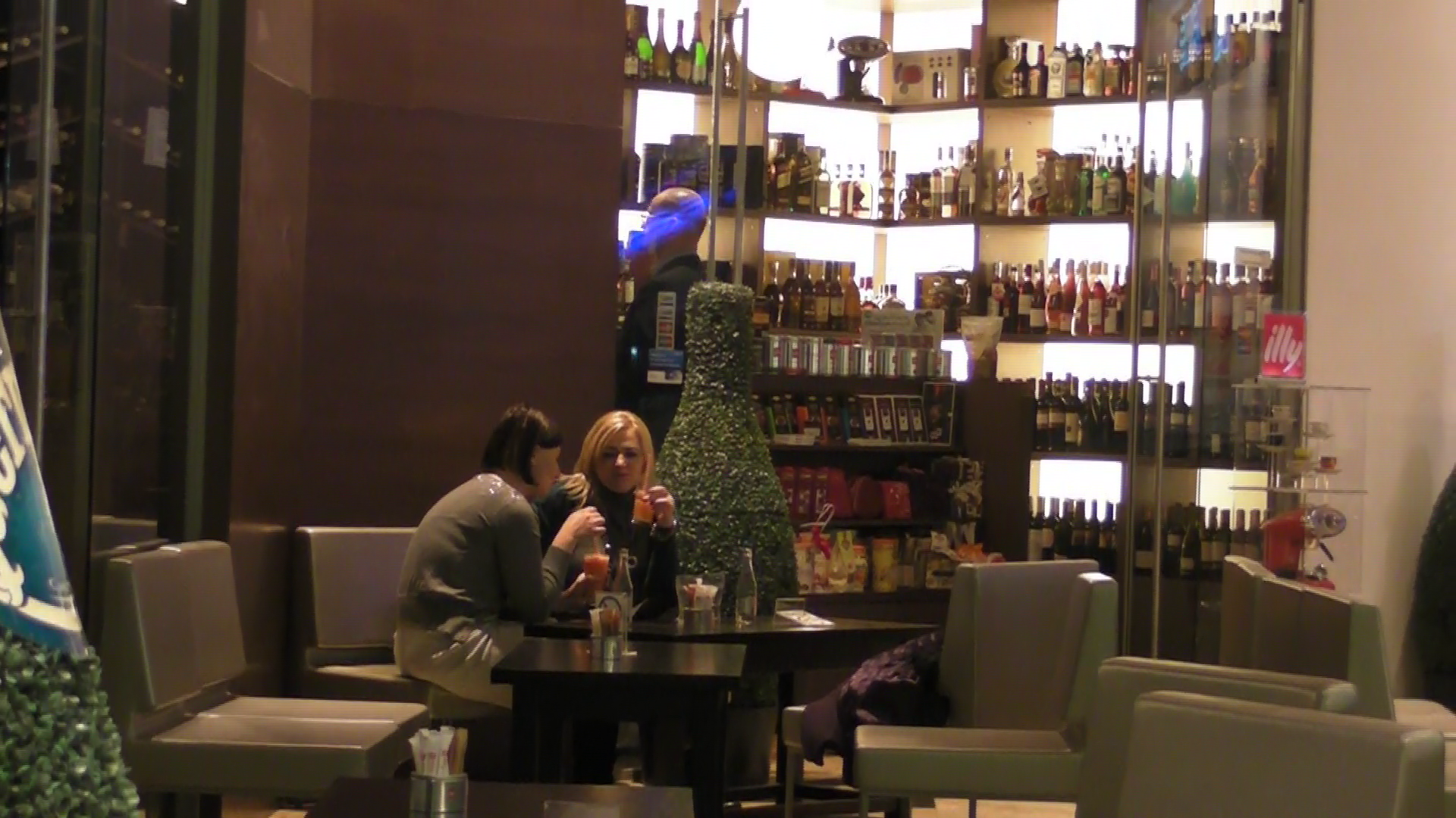 Romanita Iovan se duce aproape de tejghea si cere un sortiment de vin ales cu partenerul ei