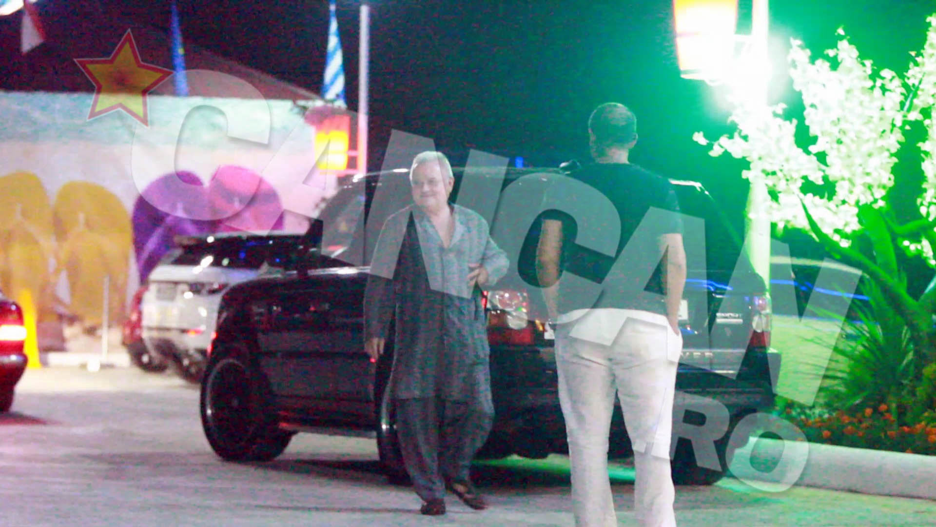 Pentru o noapte de zbucium intr-un club aerisit de pe plaja, milionarul a ales o tinuta lalaie, compusa dintr-o... haina lunga pana la genunchi, o pereche de pantaloni si sandale