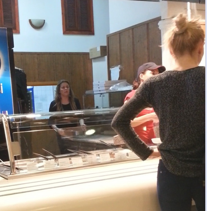 Patroana pune cu atentie tava grea pe tejghea