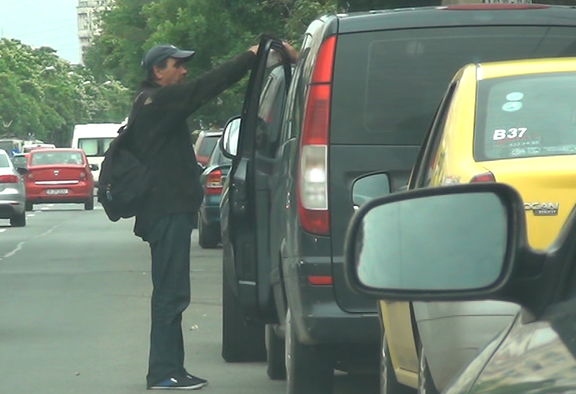 Ii da bani unui cersetor care s-a oprit langa masina lui