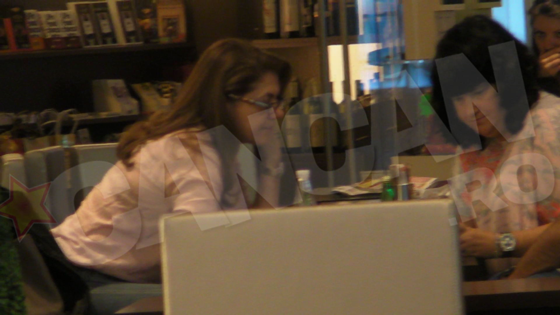 Cealalta femeie de la masa ii arata si ea ceva pe telefonul ei