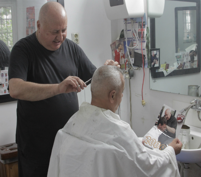 Clientul experimentatului frizer se uita la o fotografie in care nea Nicu se ocupa de freza lui Marius Niculae