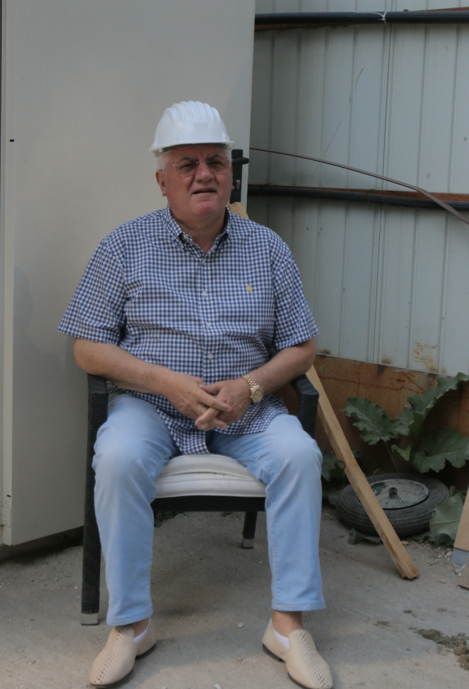 De pe scaun, brigadierul Mitica da ordine pentru muncitorii adusi din satul sau natal, Balcesti