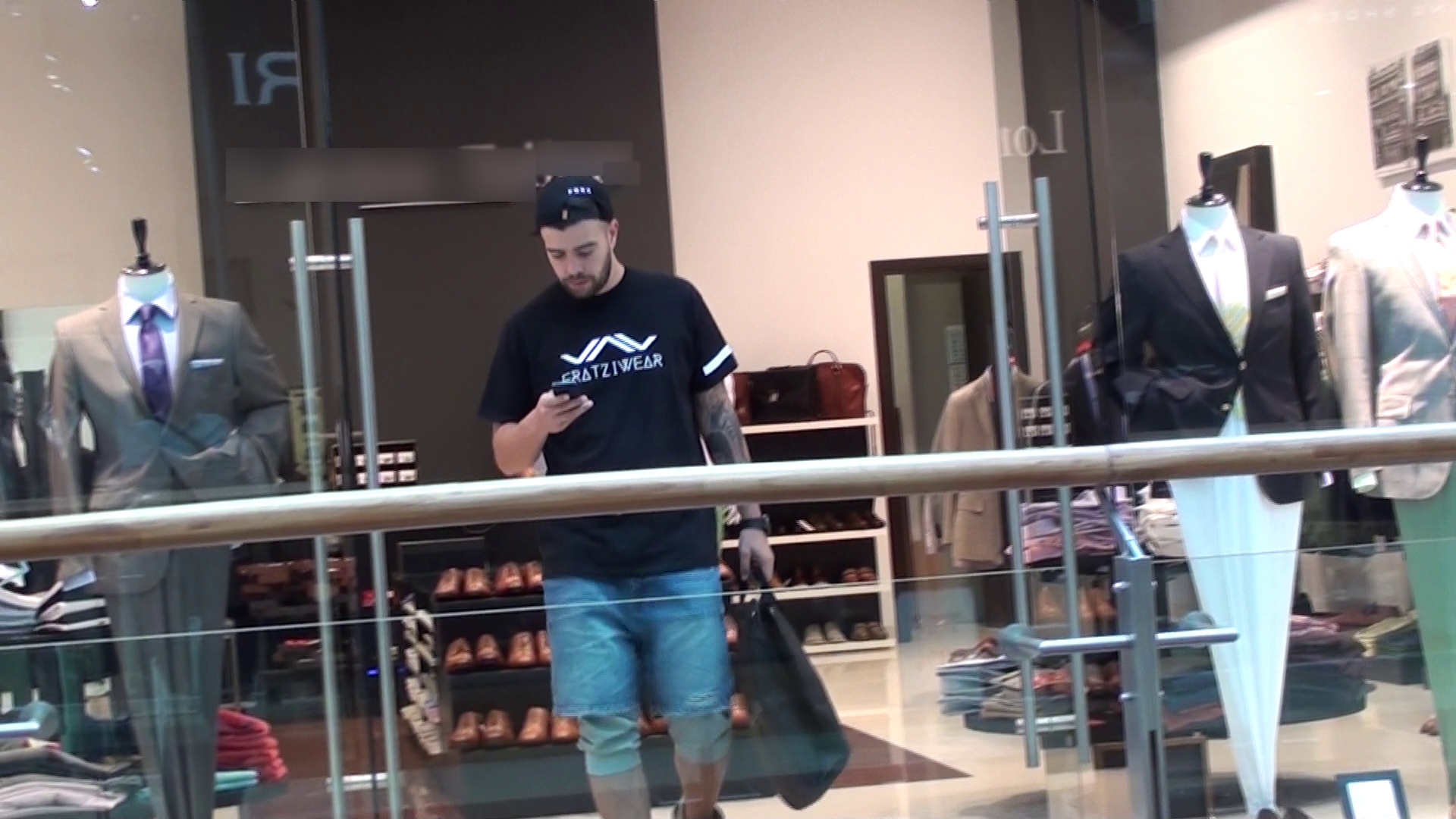 Iubitul Adelinei iese din magazin butonand telefonul mobil