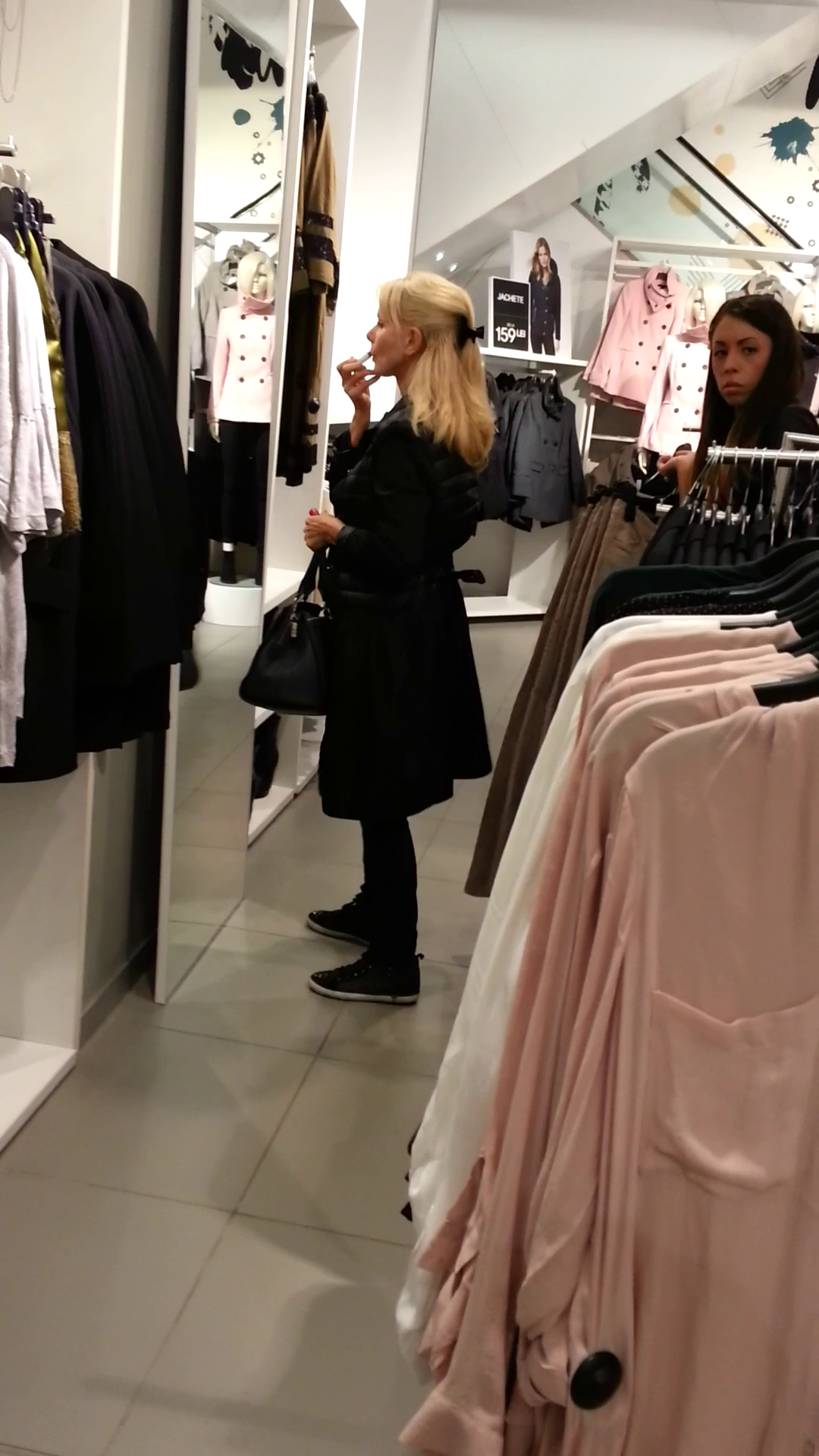 Artista se machiaza chiar in oglinda magazinului