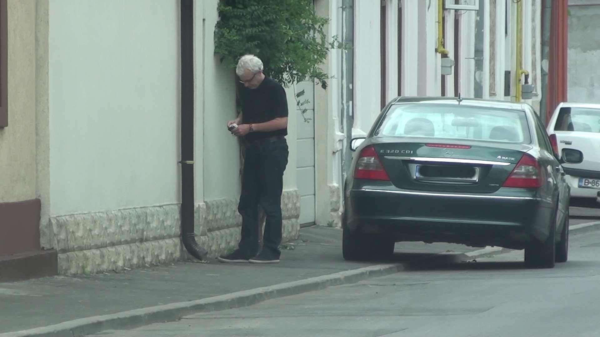 Este nerabdator sa intre in cladire, nedorind sa fie filmat sau fotografiat. Pana reuseste sa intre, afiseaza in mod repetat nerabdare si dispret