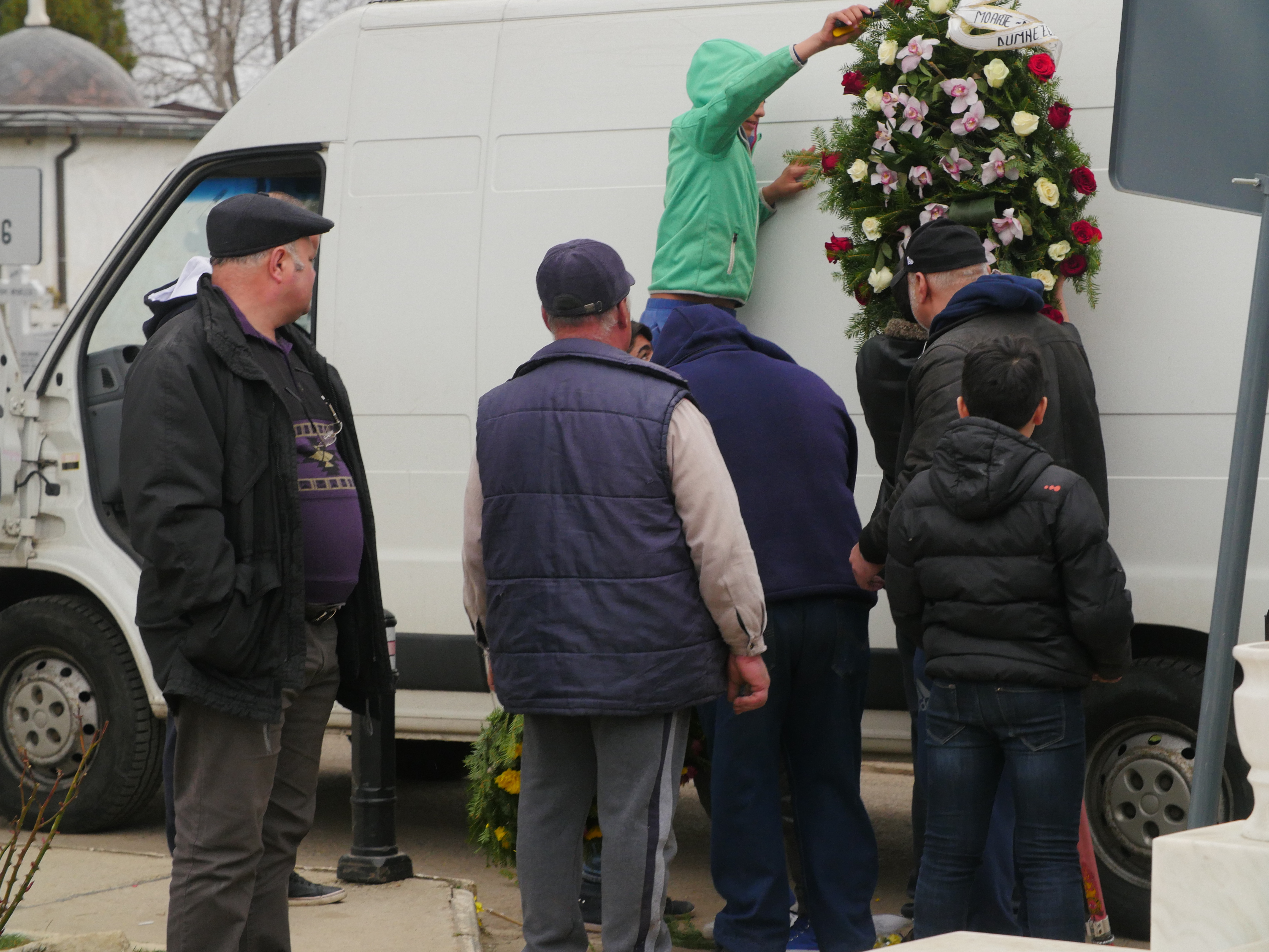 Câţiva bărbaţi au fost responsabili de transportul unei părţi din coroane şi flori, cu această dubă, însă zeci de alte persoane s-au oferit să ajute, pentru ca, odată ajuns la cimitir cortegiul funerar, cei prezenţi să constate că o mare parte din flori a dispărut pe drum.