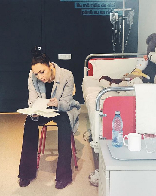 Andra stă lângă un pat de spital.