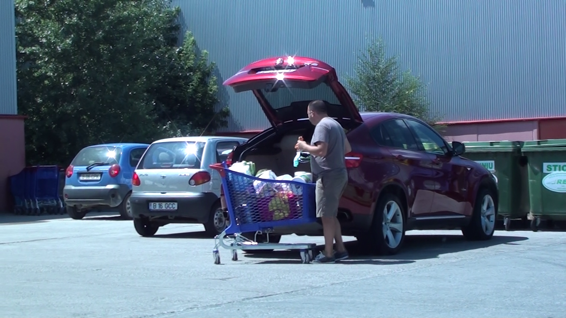 Soferul ia din masina o sacosa adusa de-acasa pentru a pune in ea cumparaturile