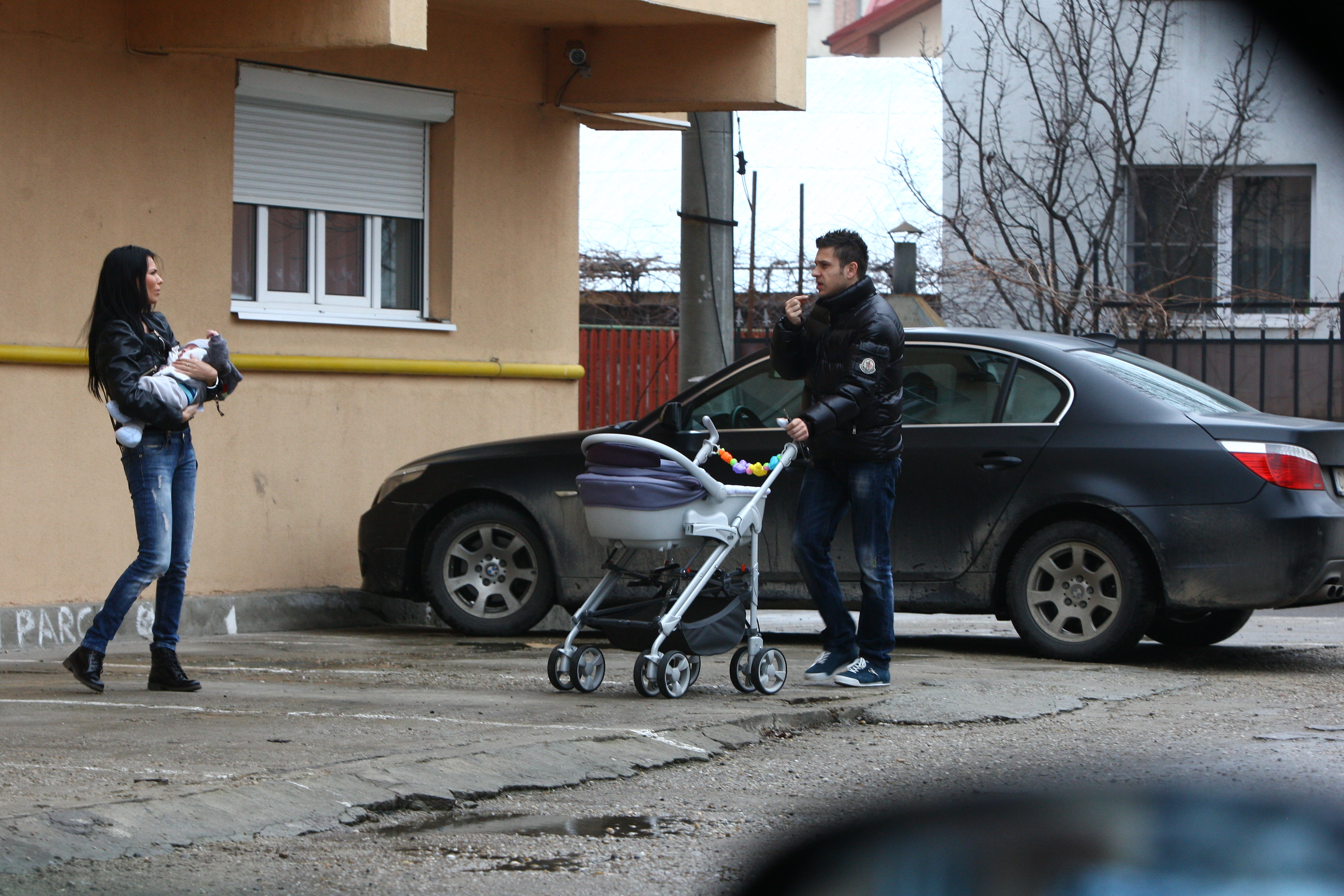 In timp ce bruneta tine copilul, sportivul impinge caruciorul gol si sparge seminte in tot acest timp