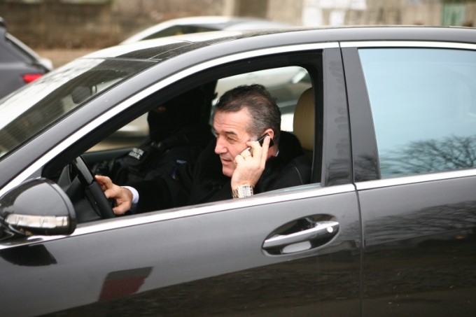 Gigi Becali, tras pe dreapta de un polițist în timp ce vorbea la
