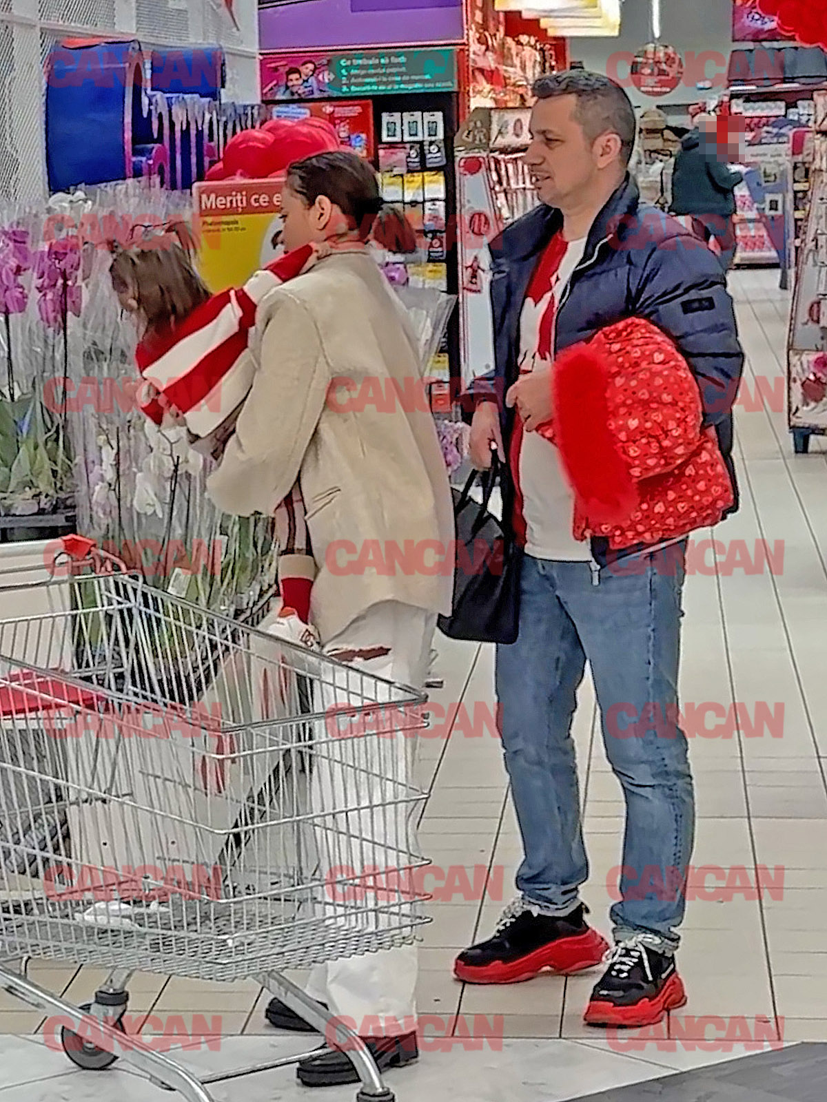 Domnul Rimă își ajută soția cărându-i geanta în timp ce Denisa o pune pe Eva Maria în coșul de cumpărături