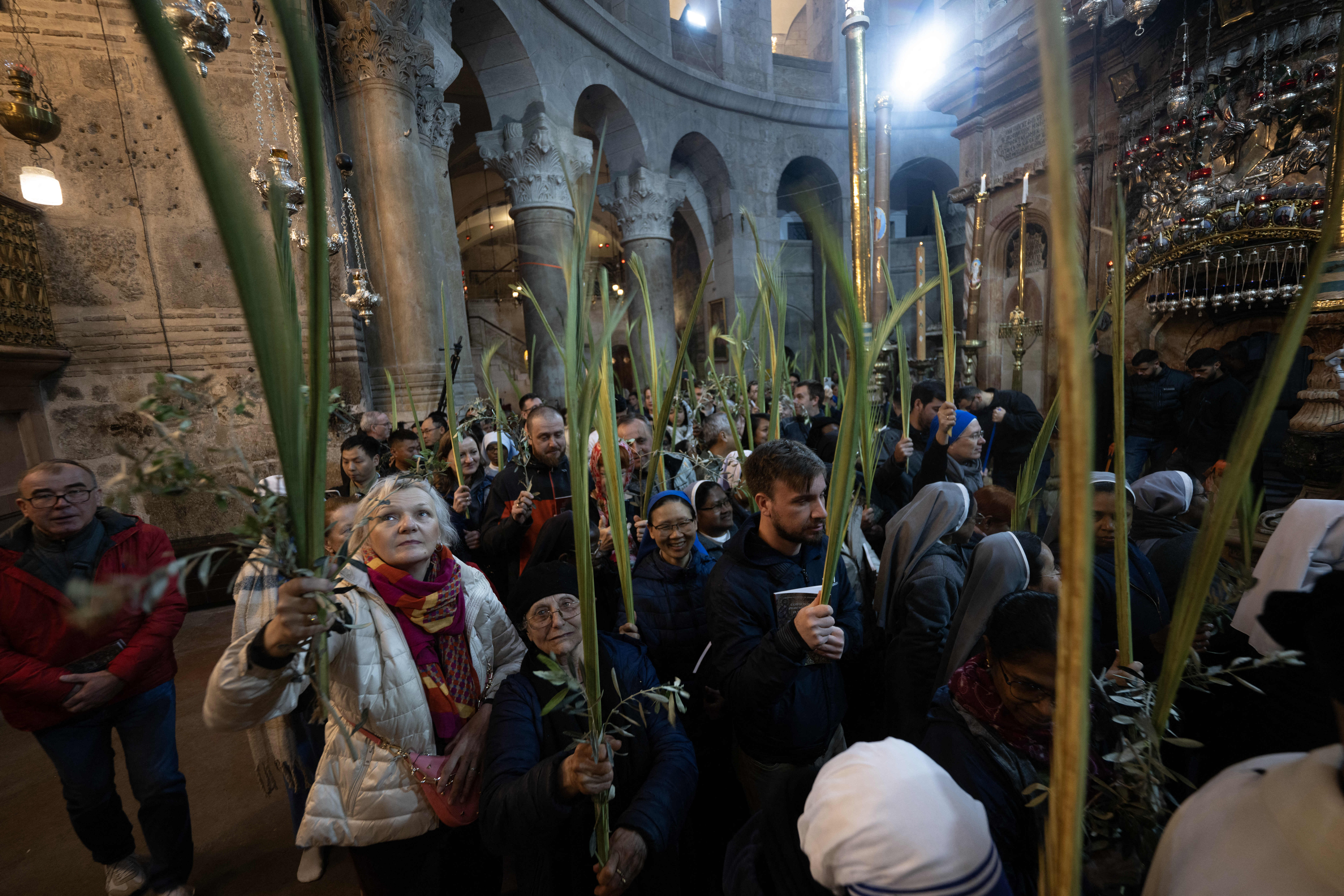 oameni la slujba in biserica, tin flori in mana si lumanari